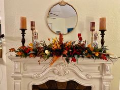 a mantel with flowers and candles on it in front of a mirror over a fireplace