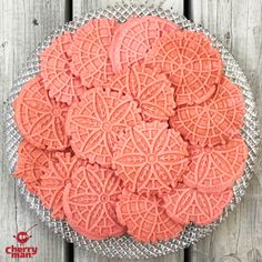 pink cookies on a glass plate sitting on top of a wooden table