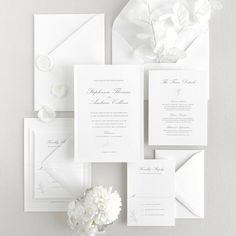 the wedding stationery is laid out with white flowers