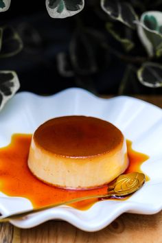 a small dessert on a white plate with caramel sauce and a gold spoon in the foreground