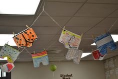 some clothes hanging from a line in an office cubicle with the word student work written on them