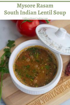 a white bowl filled with soup on top of a wooden cutting board next to tomatoes