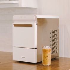 a beverage sitting on top of a wooden table next to a white refrigerator freezer