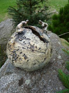 an old rock with some little figurines in it sitting on top of it