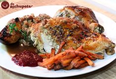 a white plate topped with chicken, carrots and gravy next to baked potatoes