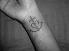 a person's arm with a cross and anchor tattoo on the left side of their wrist