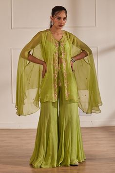 Green sheer cape with cutdana embellished floral motifs. Comes with crop top and sharara.
Components: 3
Pattern: Embroidered
Type Of Work: Cutdana,Sequin,Pearl
Neckline: Cape: Tie-up, Crop top: U-neck
Sleeve Type: Cape: Cape sleeves, Crop top: Sleeveless
Fabric: Semi Raw Silk, Georgette, Viscose Organza, Lining: Shantoon
Color: Green
Other Details: 
Attached lining
Closure:
Cape: Front drawstring
Crop Top: Back hook
Sharara: Side zip
Occasion: Cocktail,Sangeet - Aza Fashions Indian Palazzo Pants Outfit, Indian Palazzo, Palazzo Pants Outfit, Sheer Cape, Cape Set, Outfit Zara, A Line Kurta, Designer Dresses Casual, Sharara Set