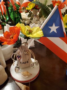 flowers in a bag on a table next to flags and other items that are for sale