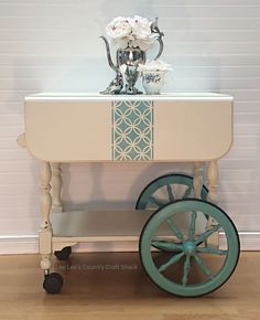 an old fashioned cart with flowers on top is sitting in front of a white wall