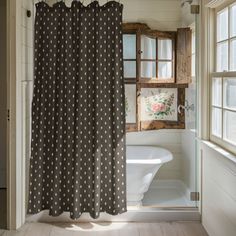 a bathroom with a shower curtain that has polka dots on it in front of a window