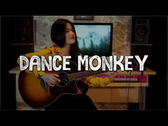 a woman sitting in front of a tv holding a guitar with the words dance monkey on it