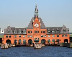 a large building with a clock on it's face next to water and docks