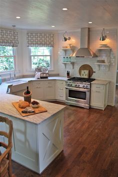 a large kitchen with white cabinets and wood flooring, along with an island in the middle