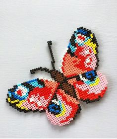 a beaded butterfly is shown on a white surface