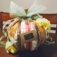 a decorative pumpkin sitting on top of a wooden table with ribbon around it's edges