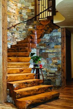 a wooden stair case next to a stone wall