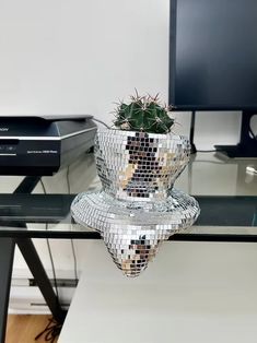 a glass table topped with a potted plant and a computer monitor on top of it