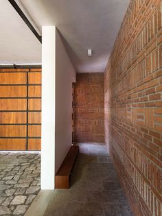 an empty hallway between two buildings with wooden doors on the side and brick walls behind it