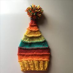 a multicolored knitted hat with a pom - pom on top