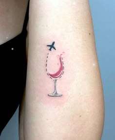 a woman's arm with a small tattoo of a wine glass and an airplane