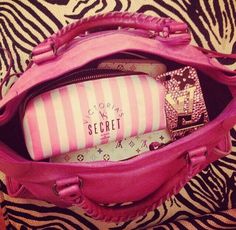 a pink handbag sitting on top of a zebra print blanket