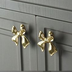 two gold bow knobs on the front of a kitchen cabinet