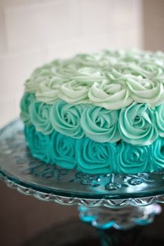 a blue and white cake sitting on top of a glass plate covered in frosting