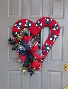 a heart shaped wreath with red, white and blue flowers on the front door for memorial day