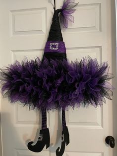 a door hanger decorated with purple tulle and black booties hanging on the front door