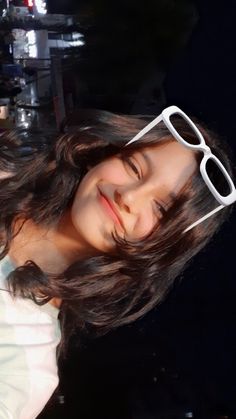 a girl with glasses on her head smiling at the camera