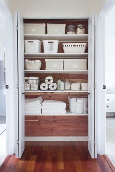 an organized pantry with white baskets and linens