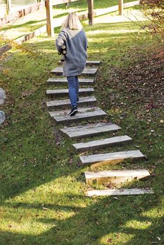 a woman walking up some steps in the grass