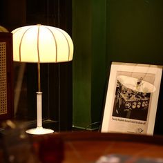 a lamp sitting on top of a wooden table next to a framed photo and radio