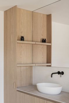 a white bowl sitting on top of a counter next to a wooden cabinet and sink