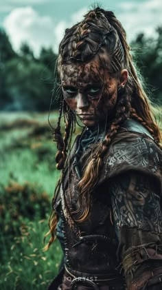 a woman with dreadlocks and tattoos on her face is standing in the grass