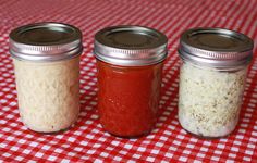 three jars filled with food sitting on top of a red and white checkered table cloth