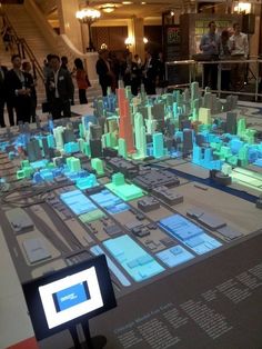 people standing around a large display in a building with many different buildings on the floor