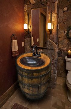 a bathroom with a sink, toilet and stone wall in it's own area