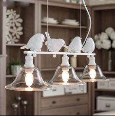 three lights hanging from the ceiling with birds on them