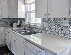 a white kitchen with black and white tile on the backsplash, counter tops and cabinets