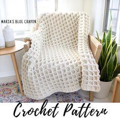 a white crocheted blanket sitting on top of a table next to a potted plant