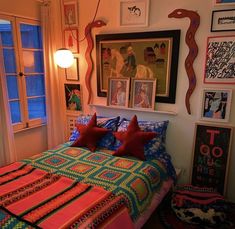 a bed with colorful blankets and pillows in a room filled with pictures on the wall