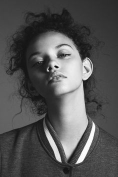 a black and white photo of a woman with curly hair looking up at the camera