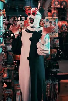 a man dressed in a clown costume holding up his hands while standing next to a store display