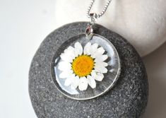 a necklace with a flower in it on top of a rock