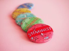 a group of buttons with the word stein on them sitting next to each other in front of a pink background