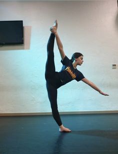 a woman is doing a yoga pose in the middle of an empty room with a tv on the wall behind her