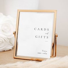 a card and gift box sitting on top of a table next to a white flower