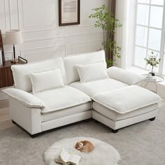 a living room with a white sectional couch and a book on the floor in front of it