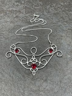 I love Victorian themed jewelry with an Edwardian, Elvish-inspired flair, and I hope I've captured it within this piece! I shall custom create this gorgeous Renaissance style necklace, in sterling silver, with three faceted gemstones of your choosing in the drop-down menu. I've shown garnet here in the images displayed. The center gemstone is 8mm round and the two sides are 4mm round. The chain will be soldered to each side and I will use a 1.2mm thick sterling box chain. I think this piece look Red Artistic Design Jewelry For Gift, Hand Forged Red Jewelry As A Gift, Hand Forged Red Jewelry For Gifts, Hand Forged Fantasy Jewelry As A Gift, Fantasy Style Hand Forged Jewelry As Gift, Artisan Red Jewelry With Artistic Design, Handmade Fantasy Round Pendant Jewelry, Fantasy Style Handmade Round Pendant Jewelry, Handmade Sterling Silver Fantasy Necklace